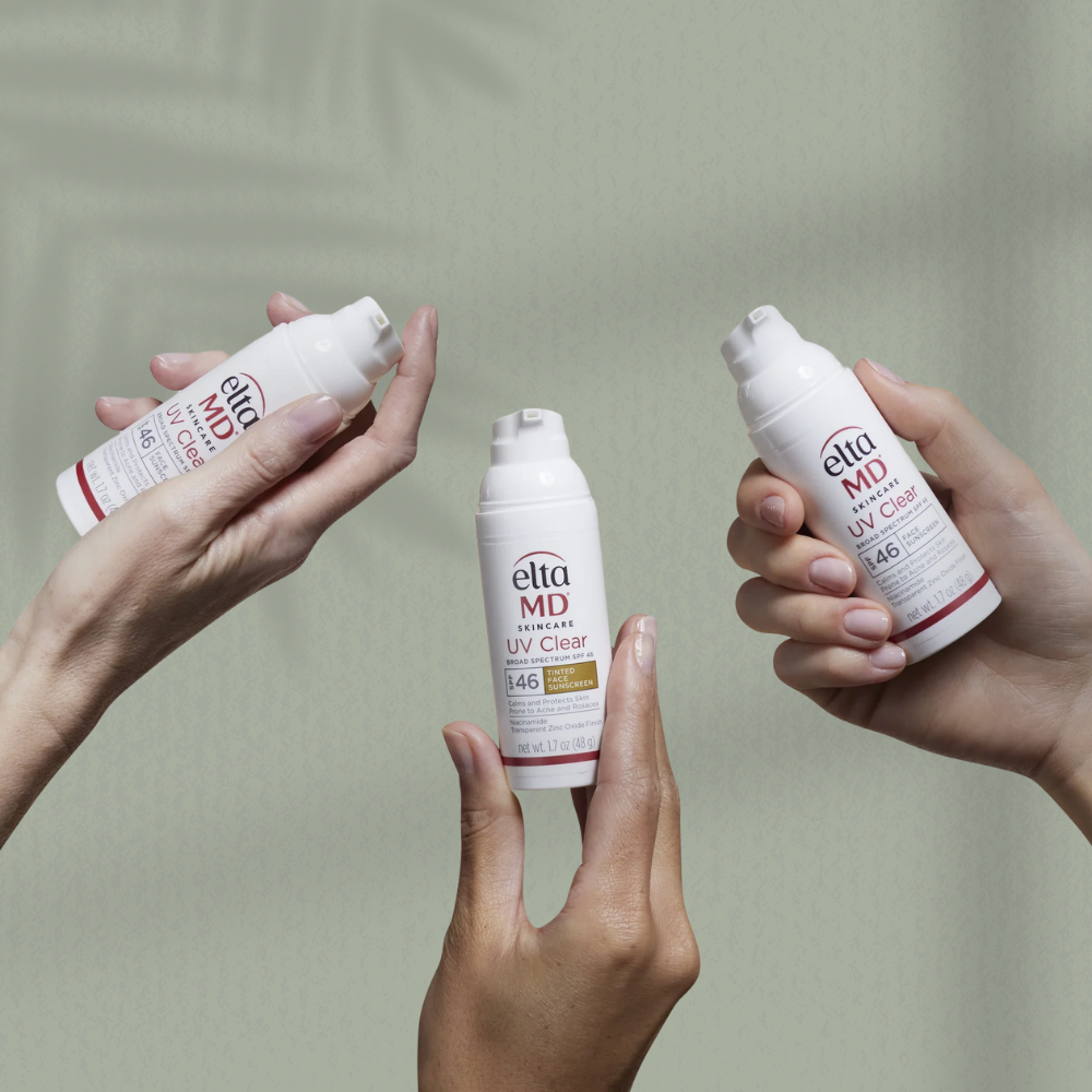 Three hands holding Ella MD skincare products against a neutral background