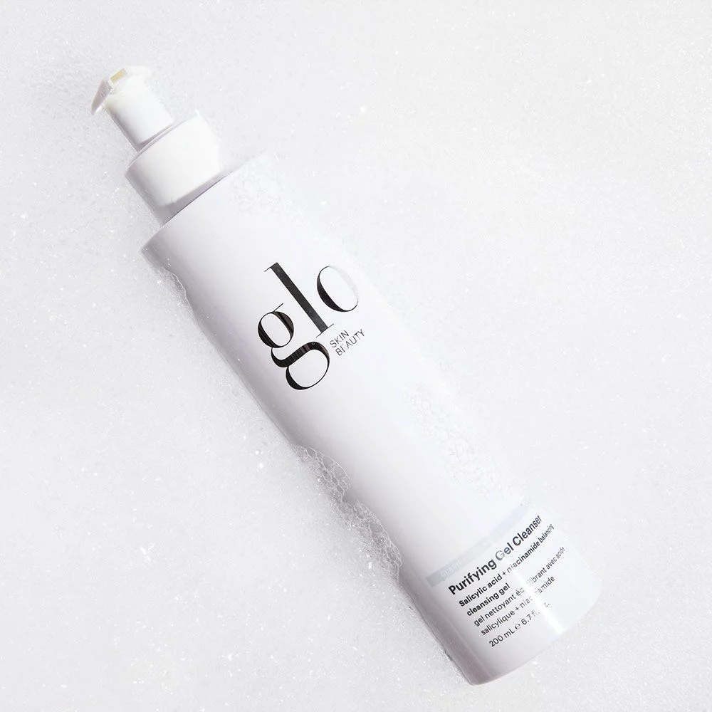 White bottle of Glo Skin Beauty Purifying Gel Cleanser on soap bubble background
