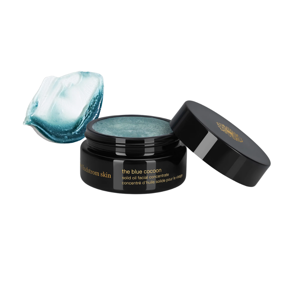 Black jar of May Lindstrom The Blue Cocoon facial oil concentrate with a scoop of the product on the left