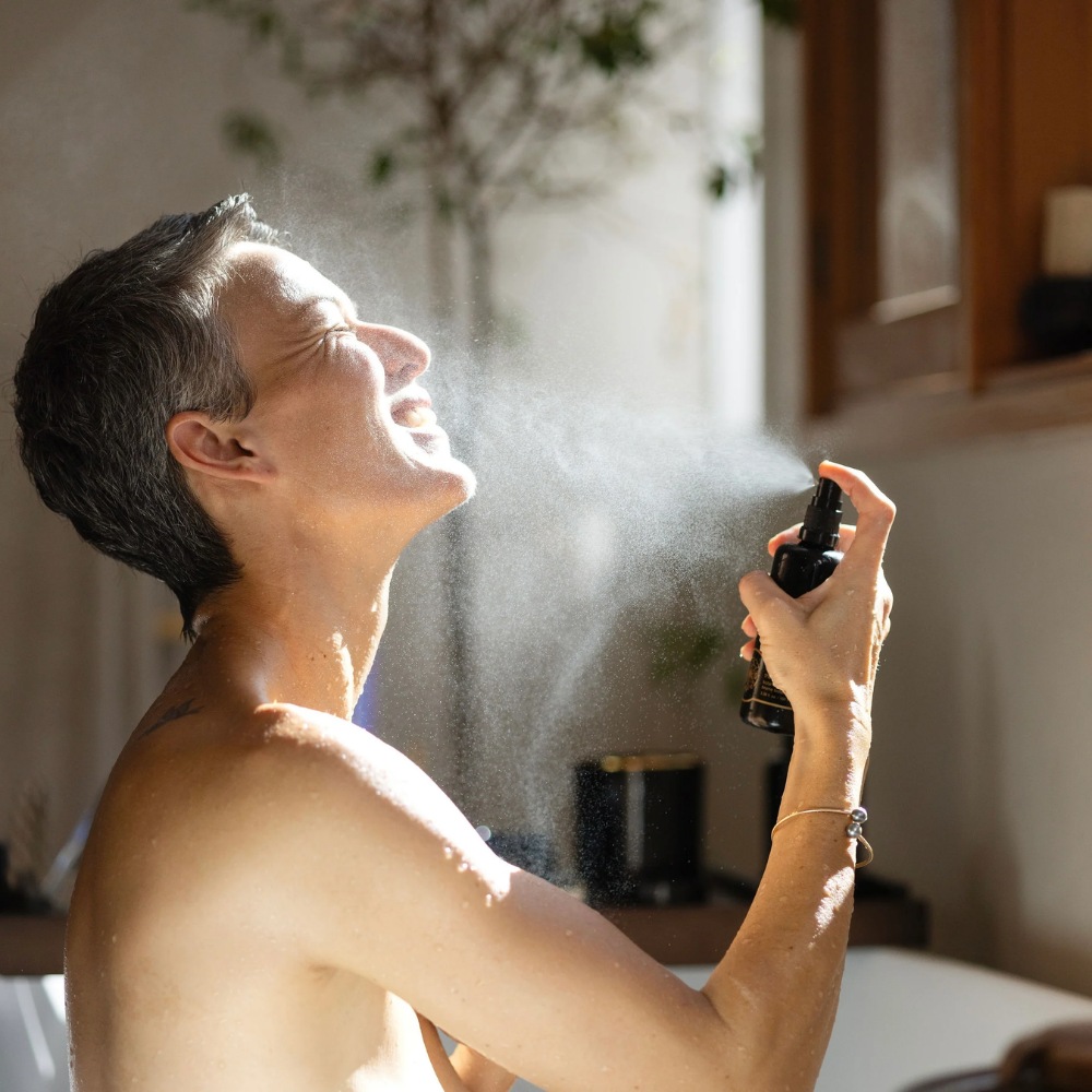 Person using a spray bottle of May Lindstrom The Jasmine Garden Facial Mist indoors with a neutral background