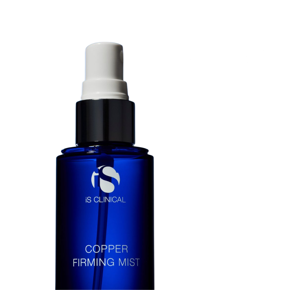 Blue spray bottle labeled iS Clinical Copper Firming Mist with a white spray cap on top spraying mist