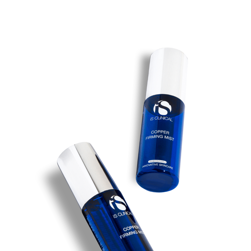 Two blue bottles of iS Clinical Copper Firming Mist with white caps