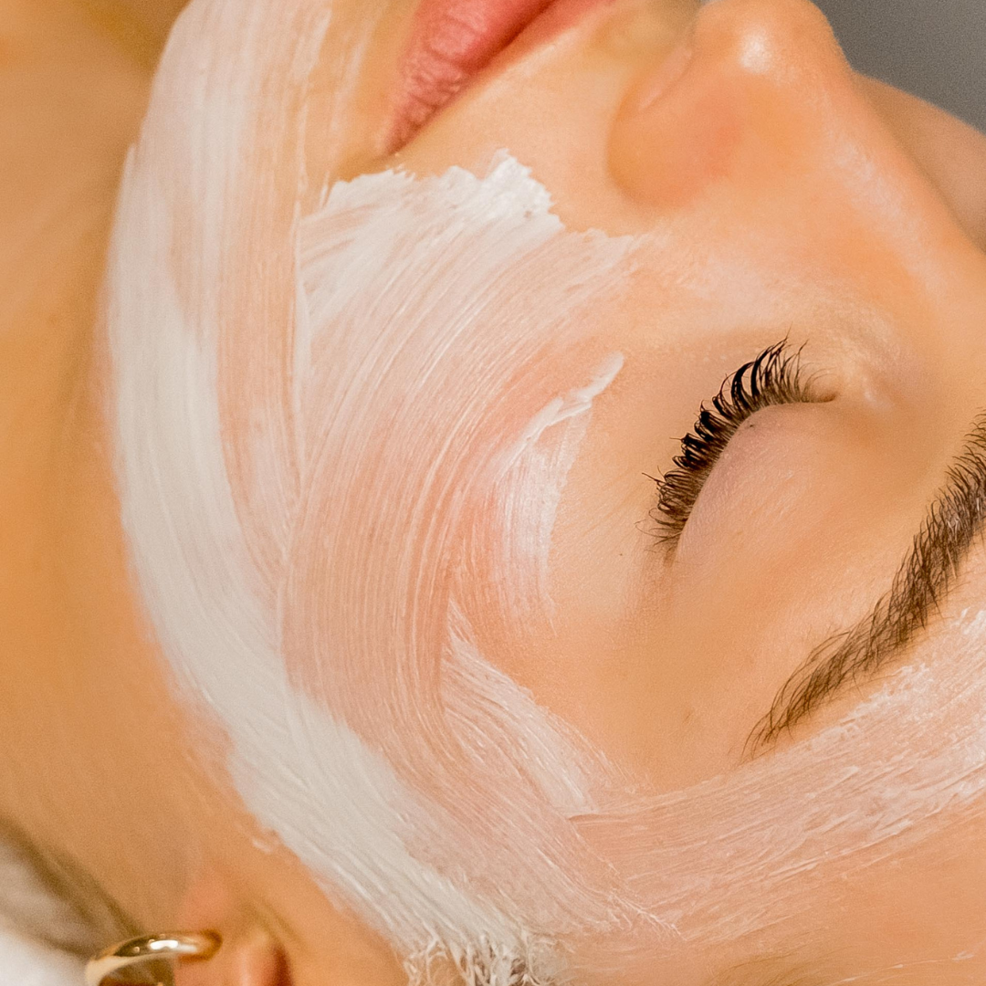 close up of a woman's face with a white cream facial mask on