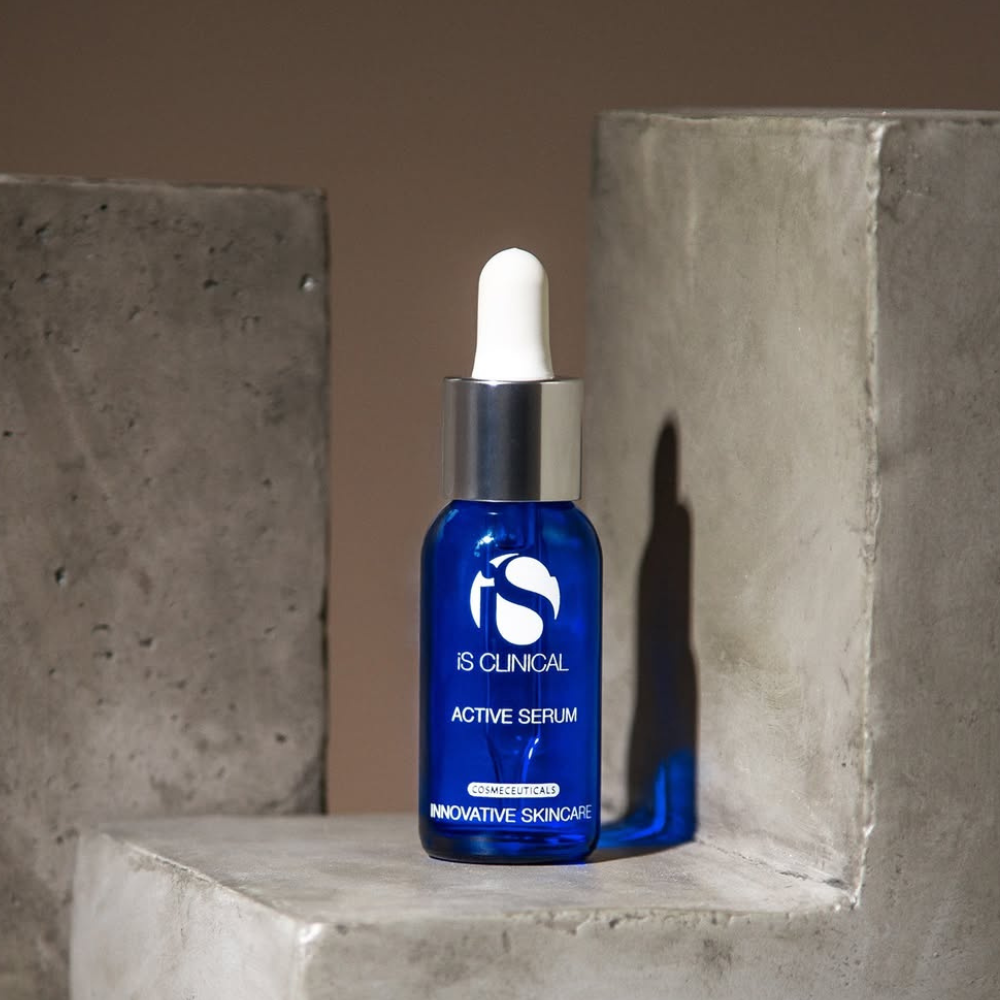 Blue serum bottle with dropper of iS Clinical Active Serum on a concrete surface