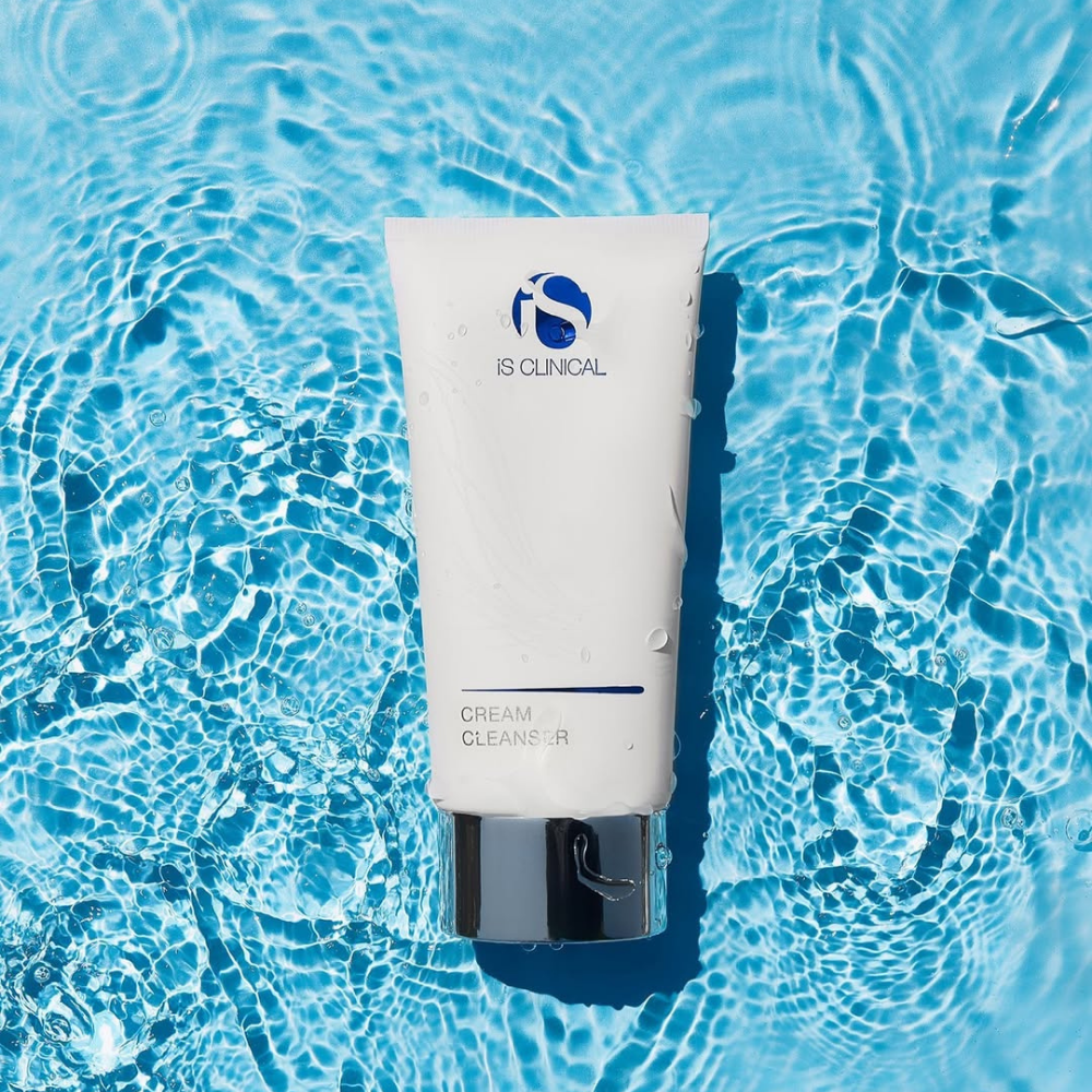 Tube of iS Clinical Cream Cleanser on a blue water background