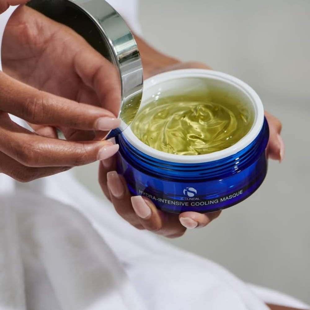 Blue jar of iS Clinical Hydra-Intensive Cooling Masque with yellow gel being scooped out by a hand