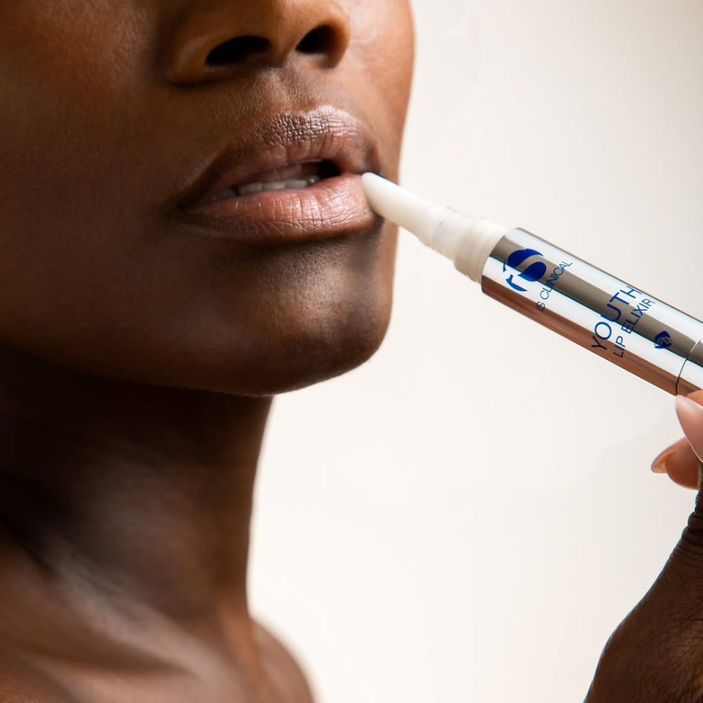 Person using the youth lip elixir from the iS Clinical Lip Duo on a blurred background
