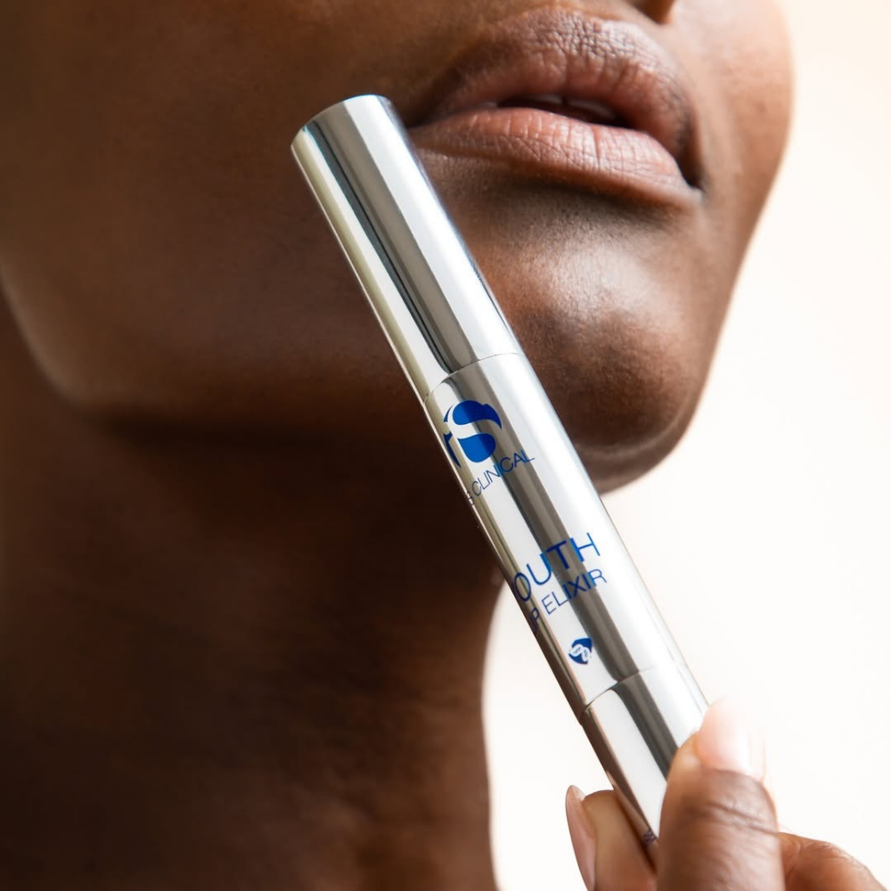 Close-up of a person holding a skincare product youth elixir from the iS Clinical Lip Duo