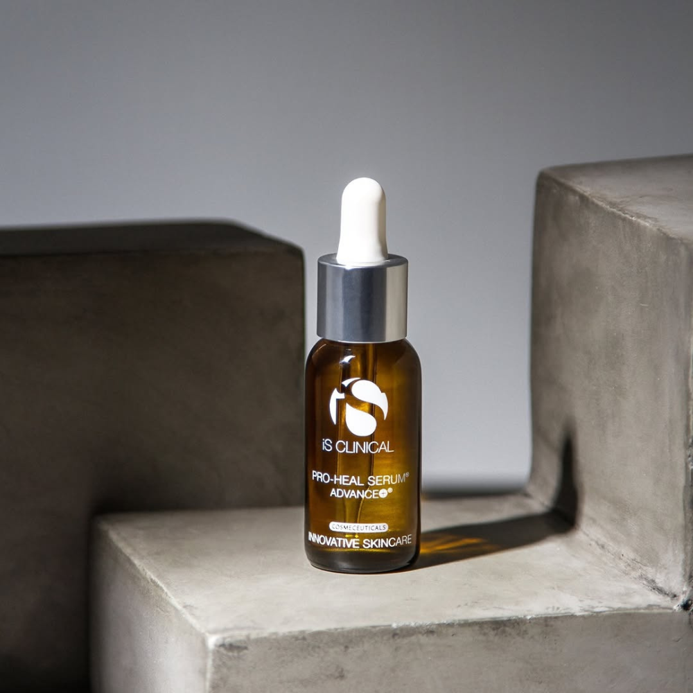 iS Clinical Pro-Heal Serum Advance+ bottle with dropper on a concrete surface