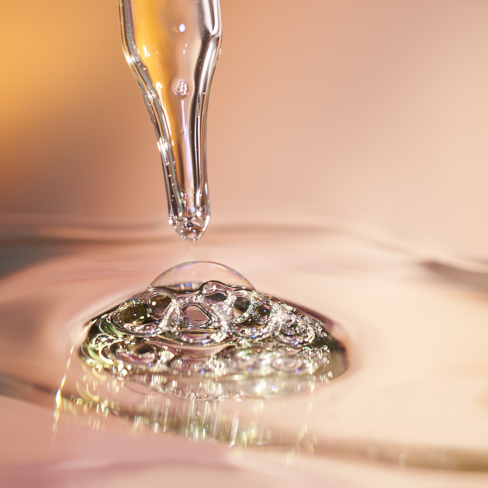 Close-up of a dropper with a drop of liquid on a reflective surface of iS Clinical Pro-Heal Serum Advance+
