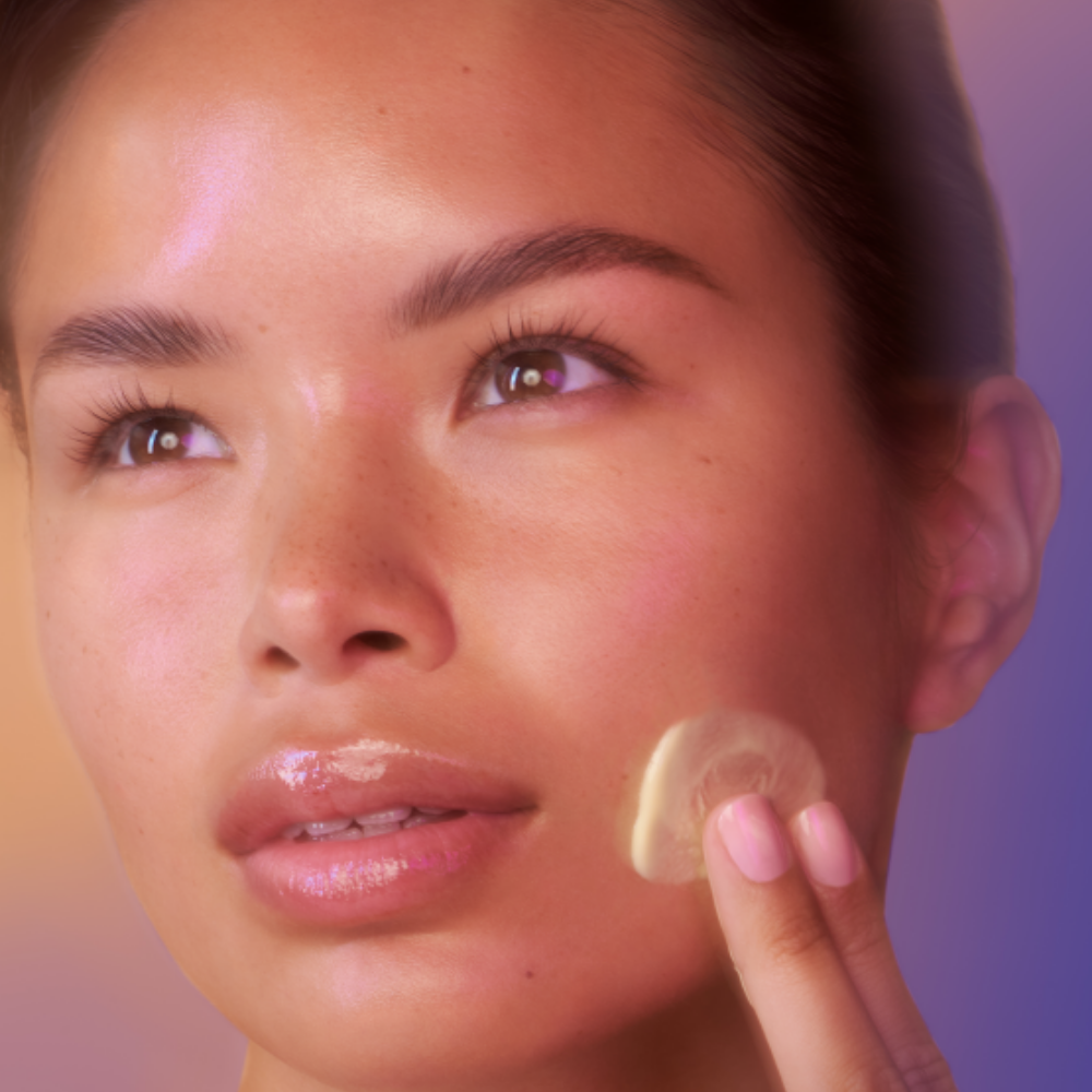 Woman applying iS Clinical Retinol + Emulsion 0.3 facial serum with two fingers on cheek