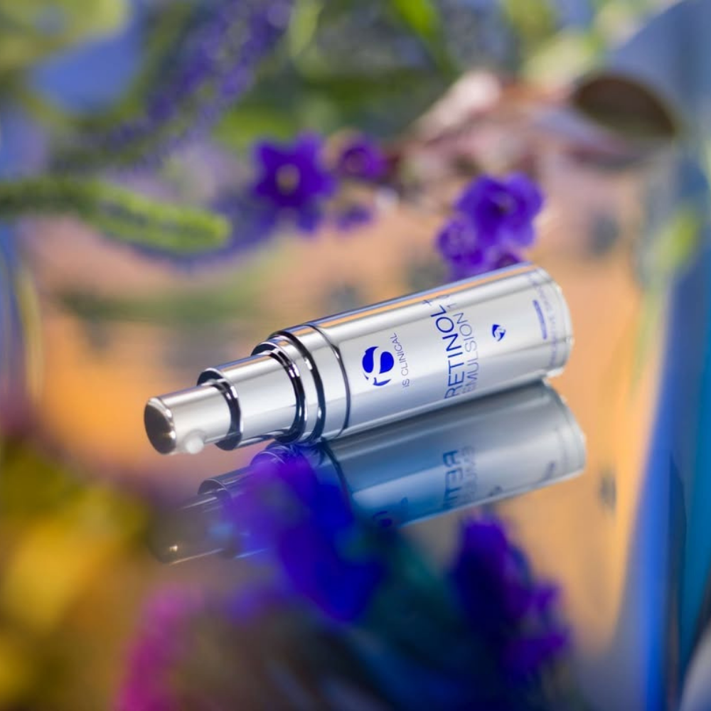iS Clinical Retinol + Emulsion 0.3 facial serum silver tube on a blurred floral background