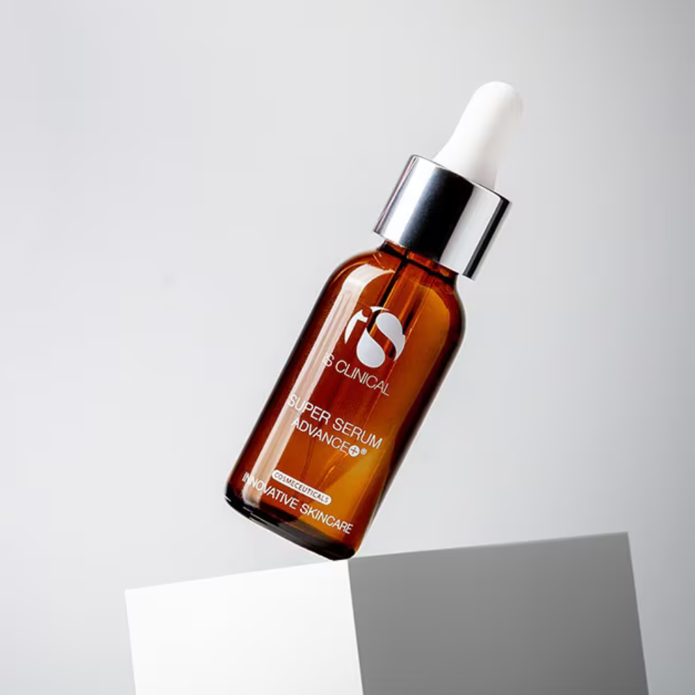 Brown bottle of iS Clinical Super Serum Advance+ with dropper on a light gray background