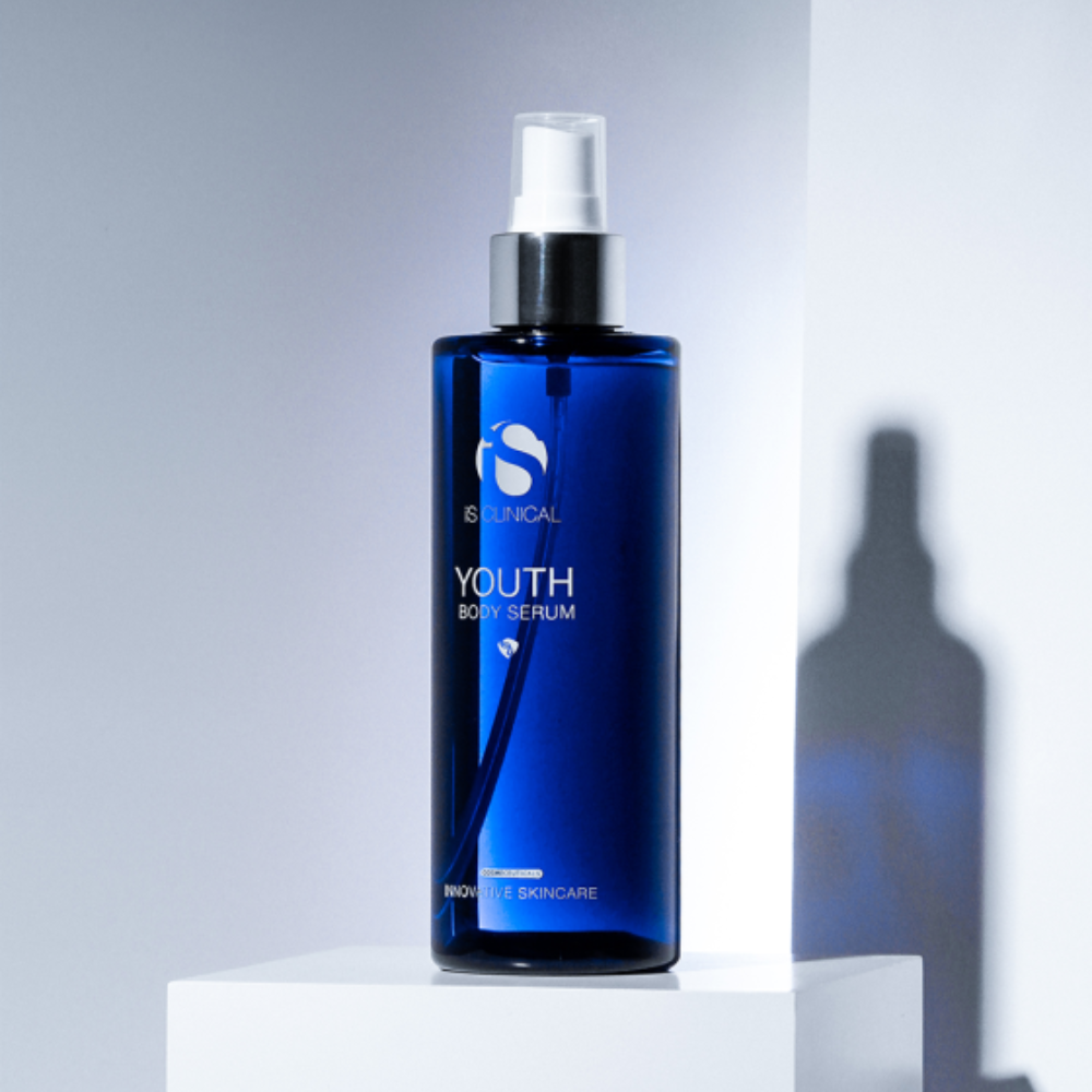 Blue spray bottle of iS Clinical Youth Body Serum on a white background