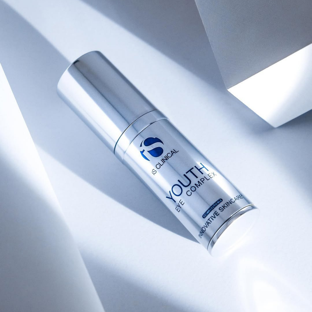 Skincare bottle labeled iS Clinical Youth Eye Complex on a light background