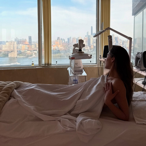 Woman sitting on a spa bed with a cityscape view from large windows