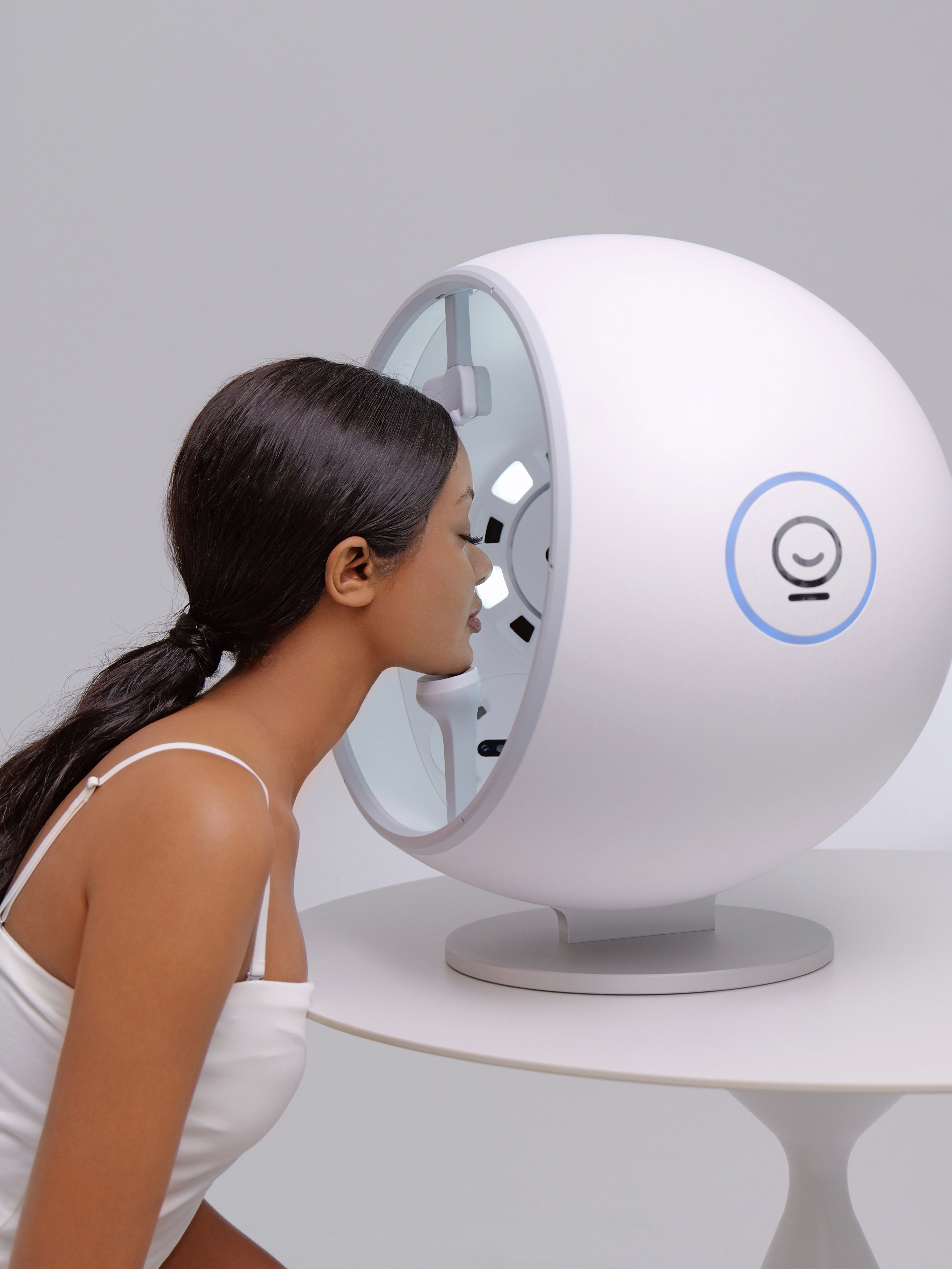 Woman interacting with the Evelab service, a sphere device on a gray background
