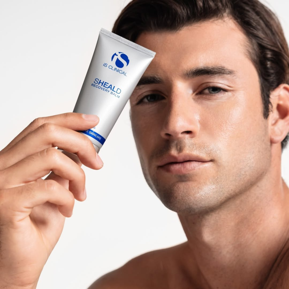 Man holding a tube of iS Clinical Sheald Recovery Balm against a white background