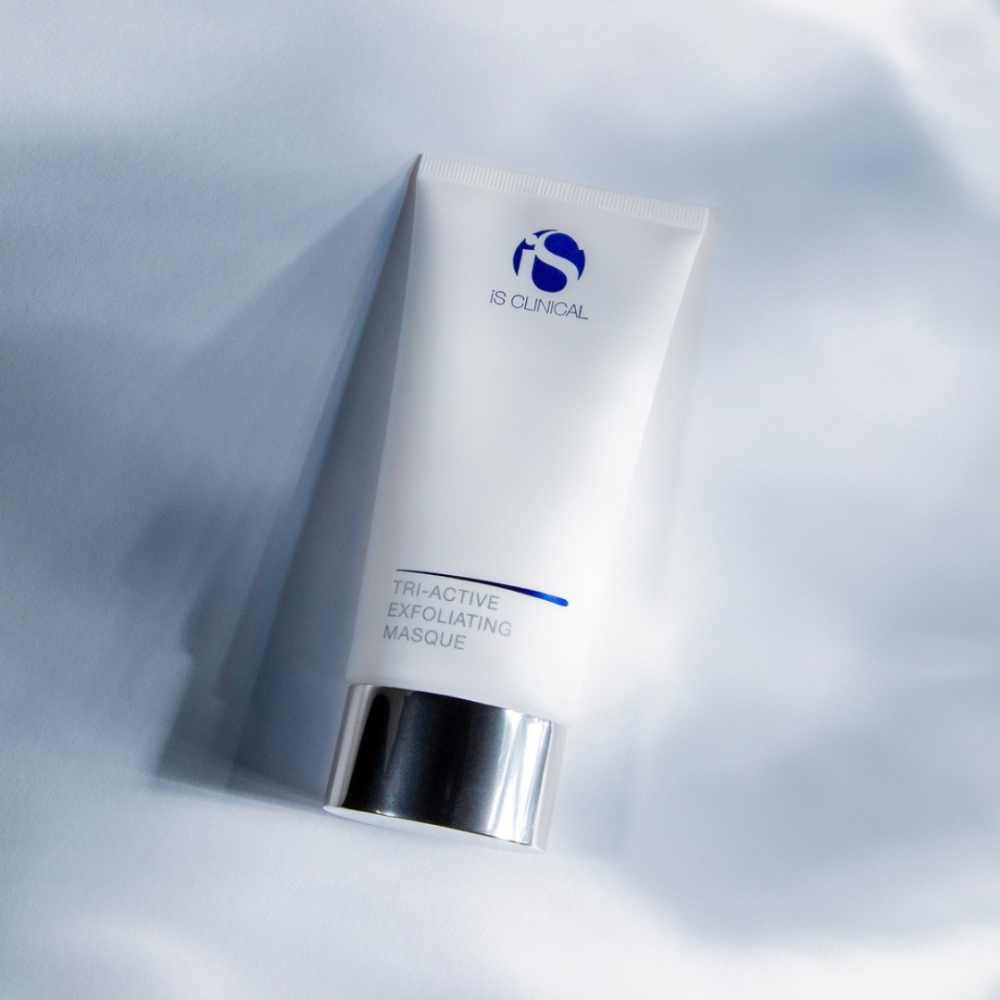 Skincare product tube labeled iS Clinical Tri-Active Exfoliating Masque on a light gray background