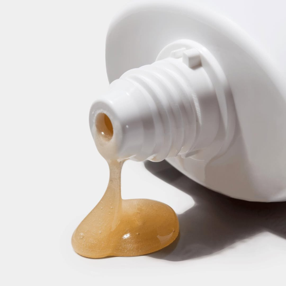 White bottle with beige cream coming out of iS Clinical Warming Honey Cleanser