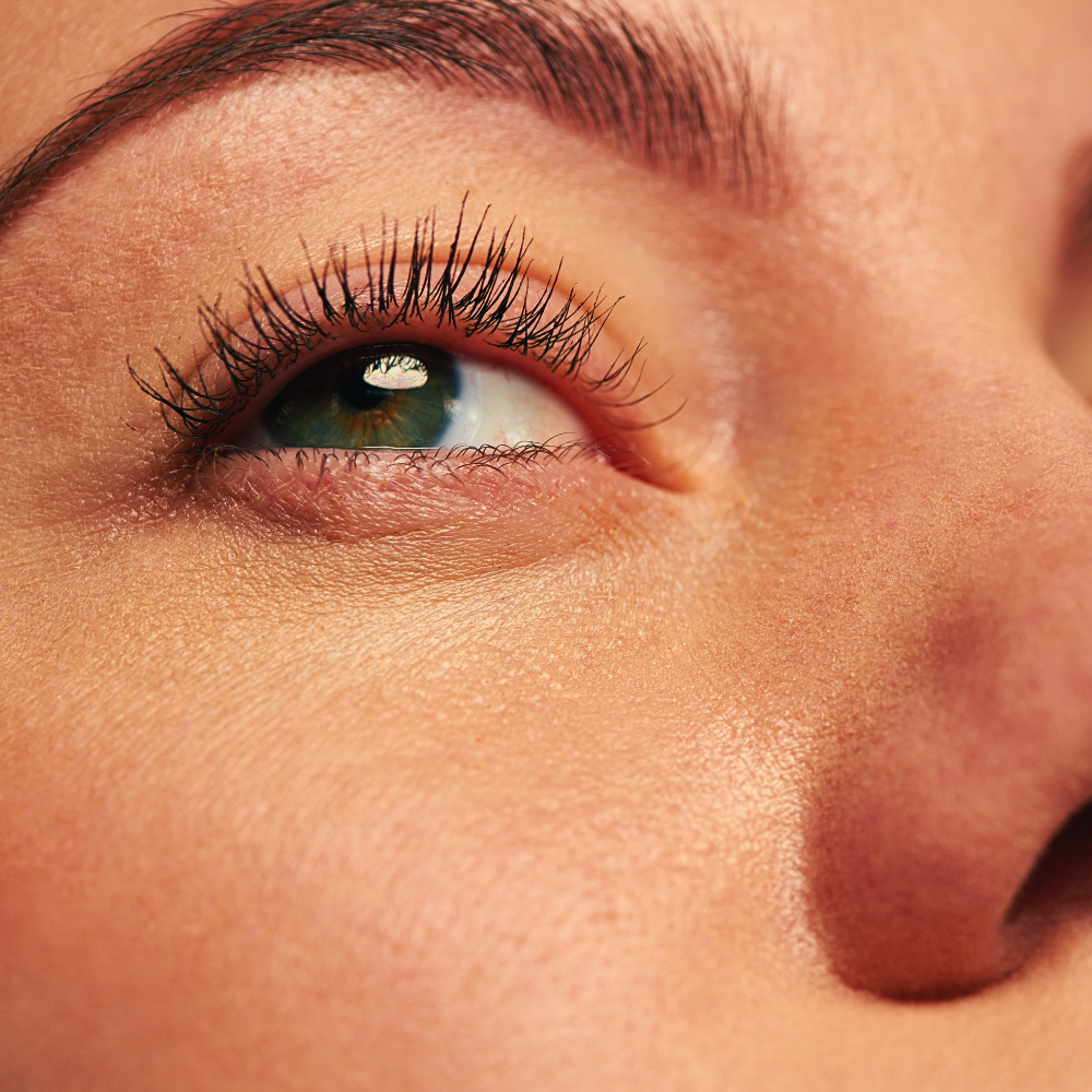 Close-up of a person's eye with detailed focus on the eyelashes and skin texture.